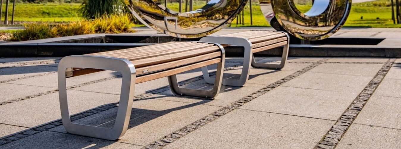 Bank voor buiten zonder rugleuning met RVS frame en houten zitvlak in moderne buitenruimte