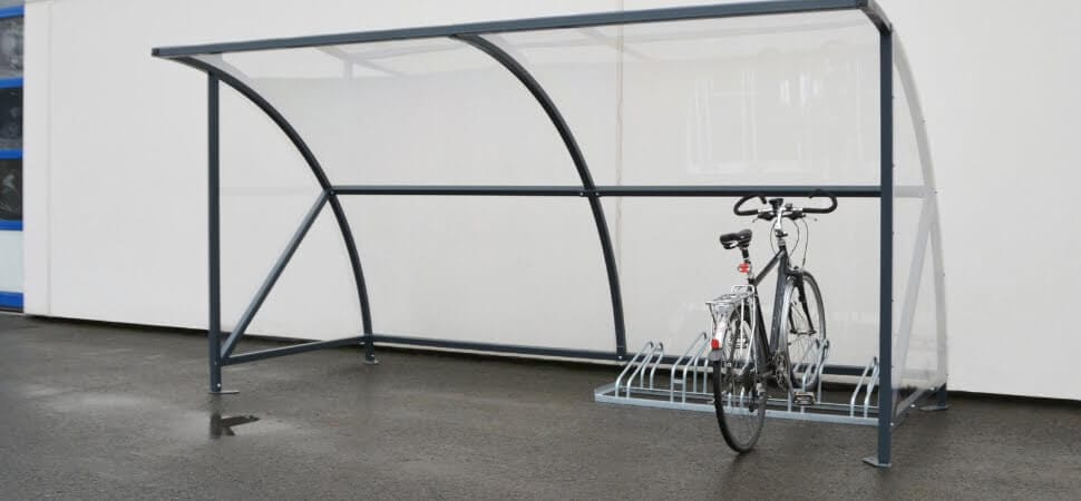 Fietsenrek geplaatst onder een verzinkte fietsoverkapping welke op asfalt is vernakerd.