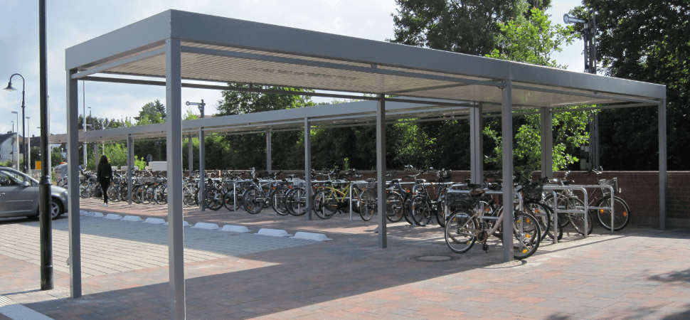 fietsoverkapping met fietsnietje van staal in kleur grijs, geplaatst bij een station.