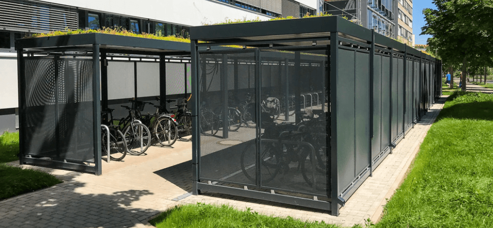 Fietsoverkapping met sedumdak en geperforeerde stalen wanden voor duurzame en veilige fietsopslag.