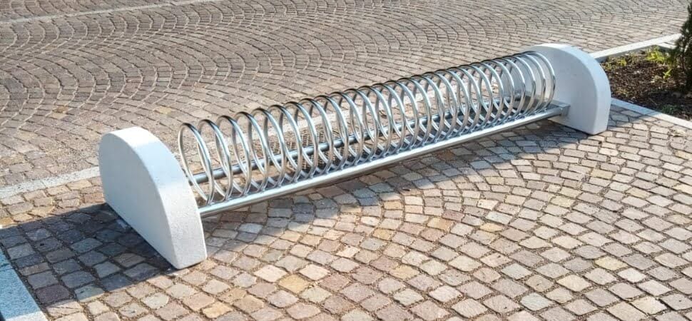 RVS fietsenrek met betonvoeten geplaatst op tegels op een stoep.