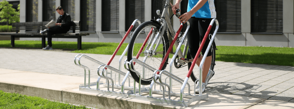 Fietsenrek met hoog-laag systeem voor ruimtebesparend parkeren van fietsen, voorzien van rode wielbeugels en geschikt voor Breeam-toepassingen.