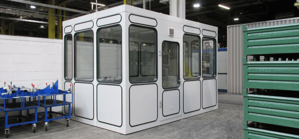 Witte prefab kantoorunit van staal met ramen en deur, geplaatst in een industriële hal, verplaatsbaar en op kleur leverbaar.