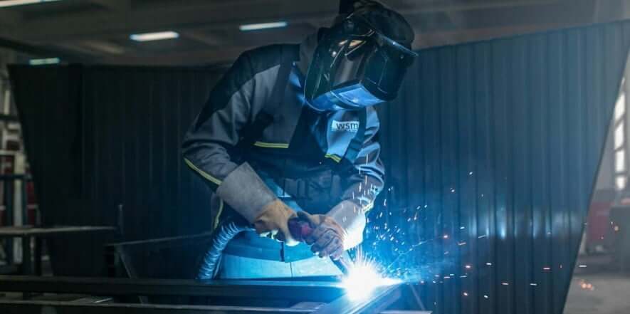 Een lasser in een fabriek last een kantoor unit voor bedrijf