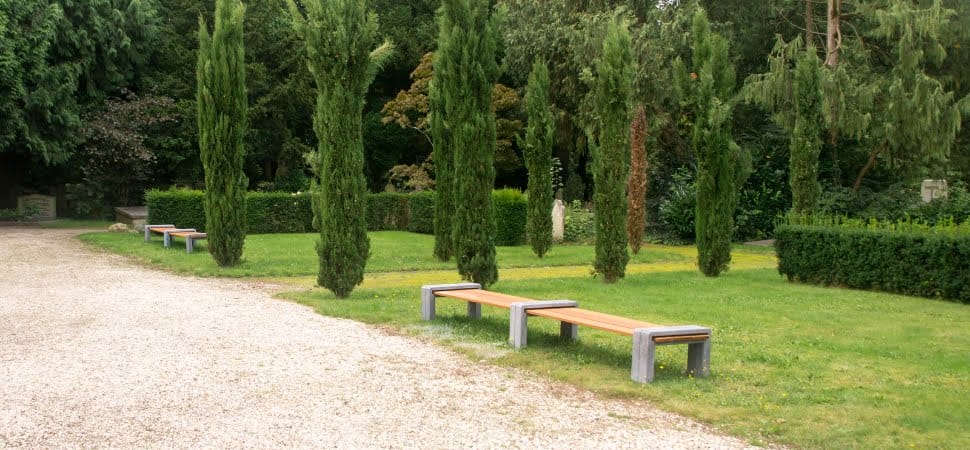 Twee banken voor buiten zonder rugleuning van beton en hout, geplaatst bij een begraafplaats.