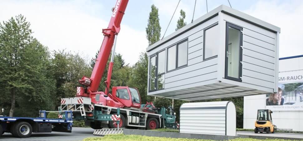 Kantoorunit voor buiten in kleur grijs, welke op z'n plek wordt gezet met een kraan.