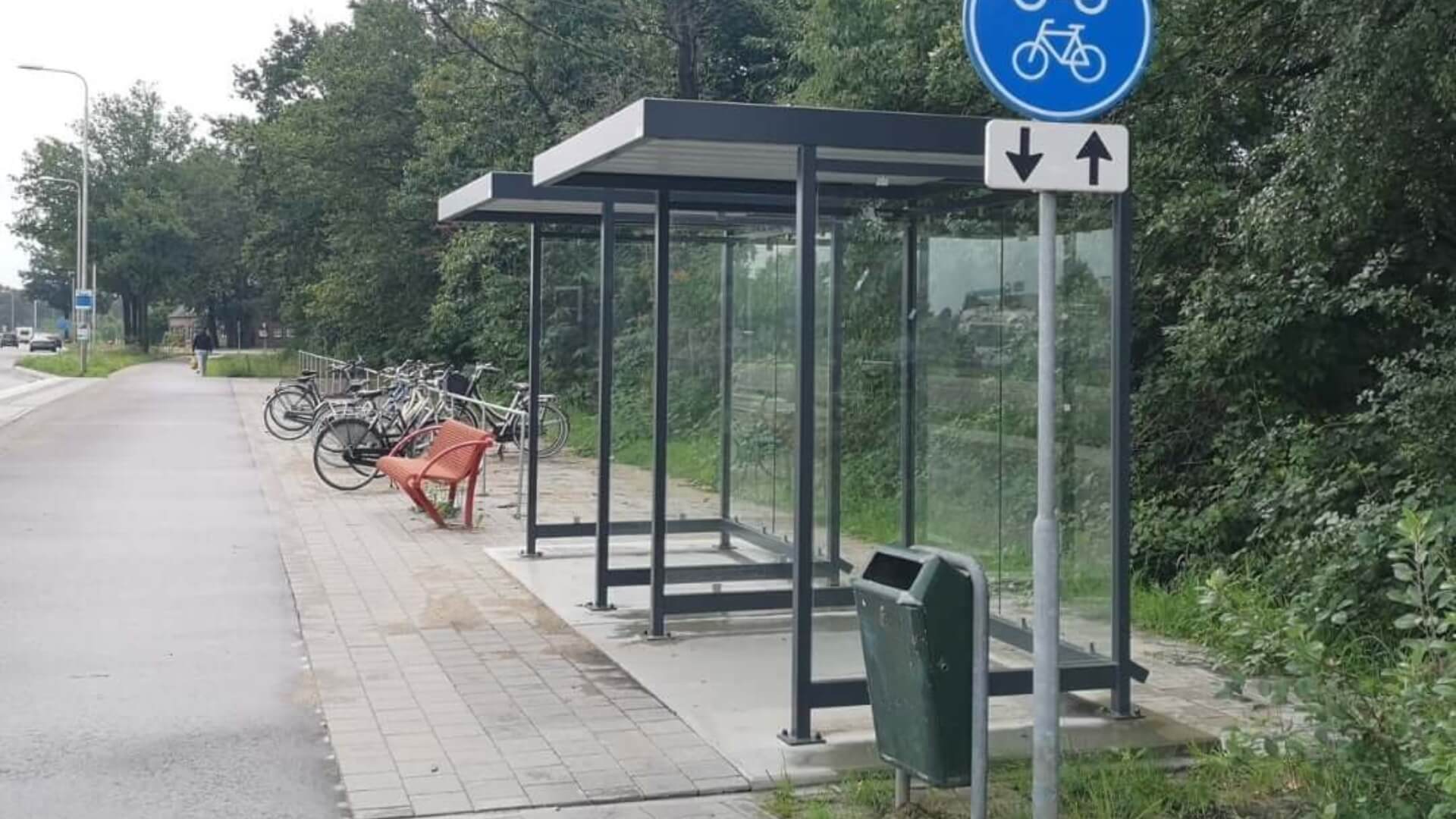 Twee bushokjes van Umfeldt met glazen zijwanden en metalen frame langs een fietspad in Nederland, duurzaam ontworpen voor openbaar vervoer.