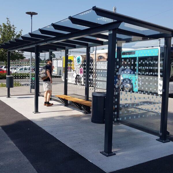 Bushokje met glazen panelen, zitbank en afvalbak op busstation