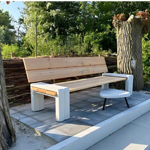 Bank voor buiten aanschaffen Bank voor buiten met onderstel van beton, zitting en rugleuning van hout, geplaatst op tegels van een tuin.