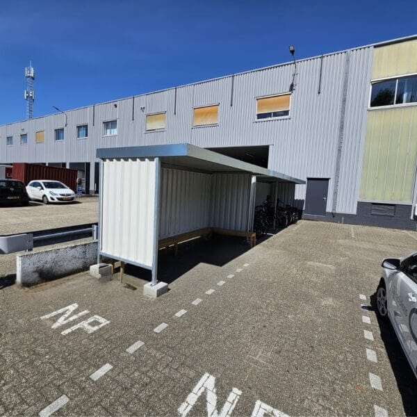 Bouwpakket rookoverkapping met zijwanden geplaatst op een industrieterrein, geschikt voor buitengebruik.
