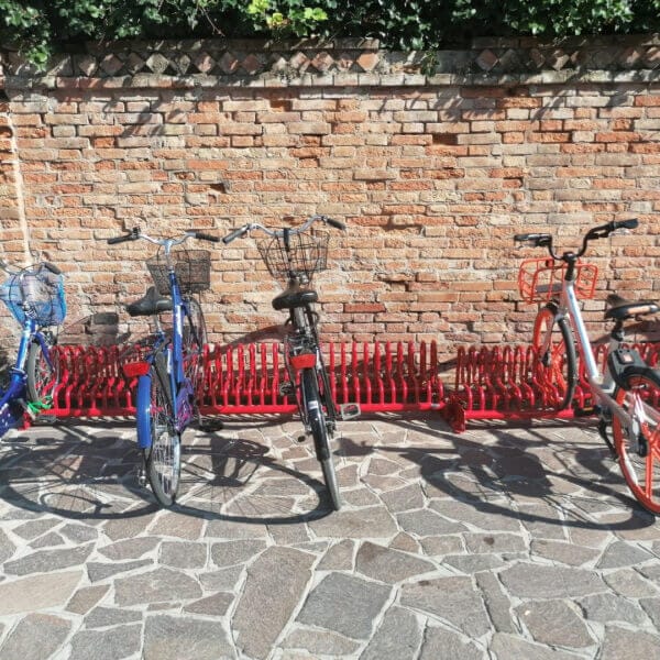 Rood fietsenrek Gamma met geparkeerde fietsen tegen een bakstenen muur
