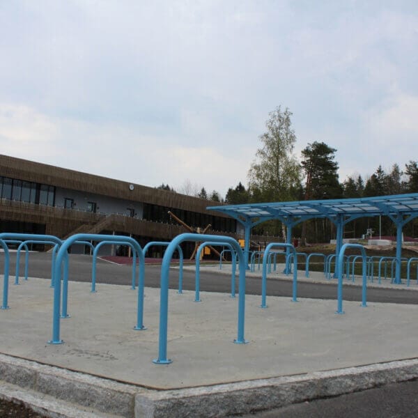 Fietsnietje Roma blauw direct aanschaffen Blauwe fietsenrekken Roma op een plein met overdekte fietsenstalling