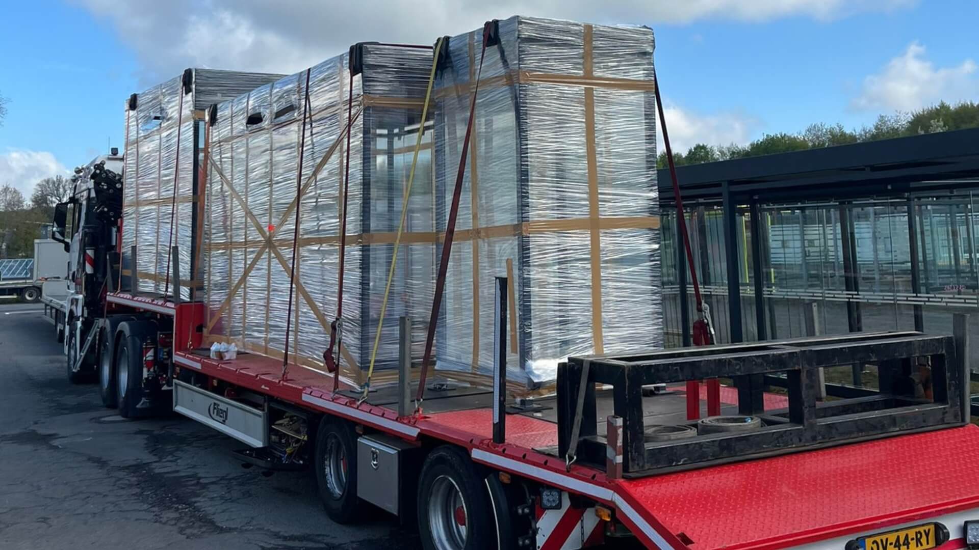 Trailer met ingepakte rokershok, fietsoverkapping en wachtershuisje, gereed voor levering door heel Nederland