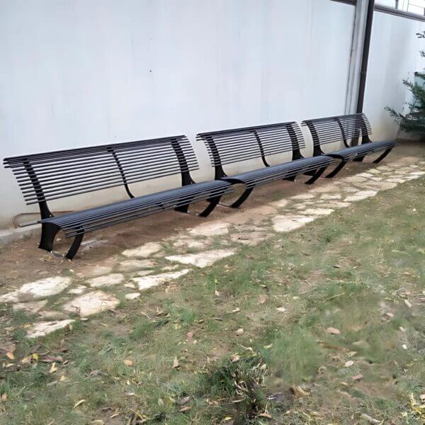 Metalen parkbank direct online bestellen Zwarte metalen parkbanken met een modern design, geplaatst langs een tuinpad.