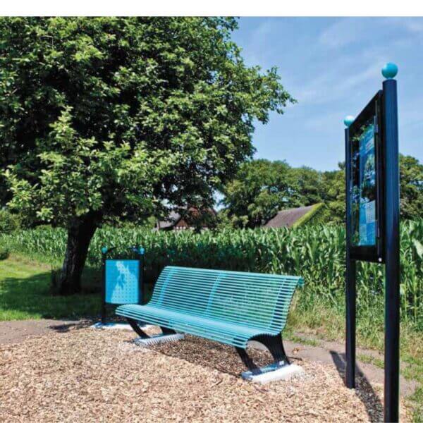 Parkbank metaal kleur blauw bestellen Stalen parkbank met zwarte frame en blauwe zitgedeelte, geplaatst in een landelijk gebied met veel groen.