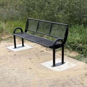 Zwarte parkbank van staal met rugleuning geplaatst op tegels in een natuurlijke omgeving