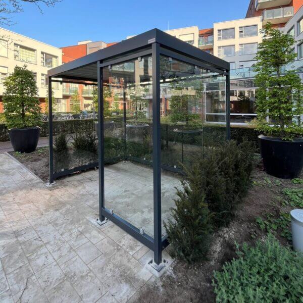 Rookabri 3x2meter umfeldt antraciet aanschaffen Rookabri van verzinkt staal met glaswanden geplaatst bij appartementencomplex