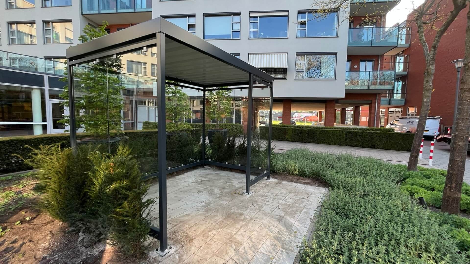 Rookabri met glazen panelen en stalen constructie geplaatst in binnentuin zorgcomplex