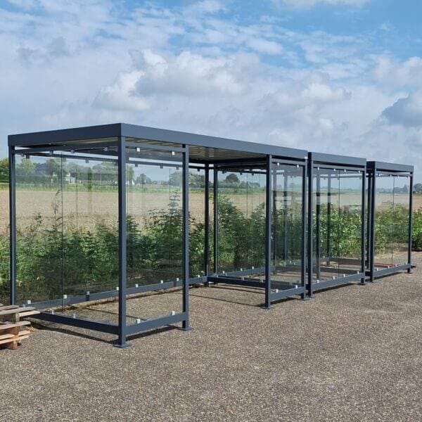 Rookoverkapping voor montage op asfalt kopen Drie gekoppelde rookoverkappingen van staal en ESG-glas, opgesteld op een buitenterrein, uitgevoerd in RAL-7016.