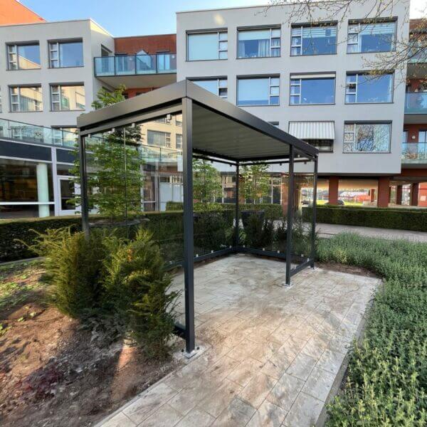 Rookoverkapping voor senioren direct online aanschaffe Rookoverkapping met glazen wanden en stalen frame geplaatst bij wooncomplex