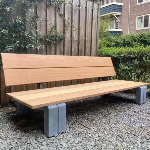 Houten tuin lounge bank met betonnen onderstel in moderne tuinomgeving