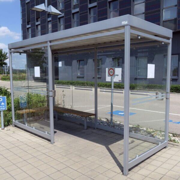 Rokersafdak kopen – comfortabele en duurzame overkapping Rokersafdak met een stevig metalen frame en glazen wanden, voorzien van een houten zitbank.