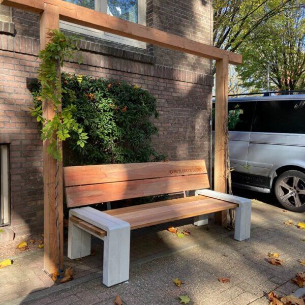 Buurtbank-online-aanschaffen Stijlvolle houten buurtbank met betonnen onderstel en gegraveerde rugleuning.