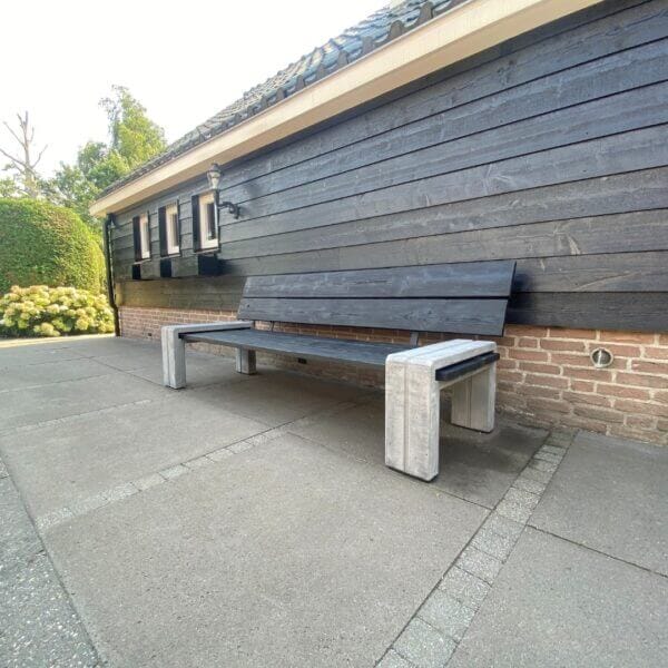 Buurtbankjes kopen Buurtbankjes met gerecycled betonnen onderstel en houten zitvlak geplaatst tegen muur van een woonboerderij.
