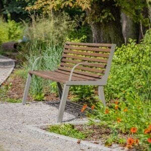 Stijlvolle buitenbank met metalen frame en houten latten geplaats in een bloemrijke omgeving.