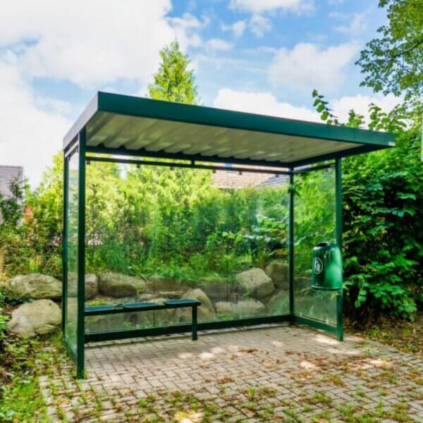 Groen bushokje met glazen wanden en stalen frame in de openbare ruimte