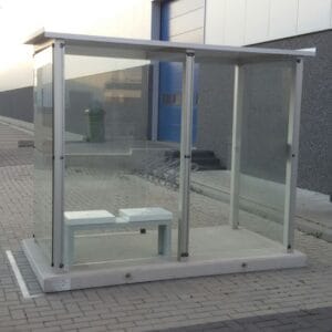 Prefab rookabri met glazen wanden en geïntegreerde zitbank, geleverd op een prefab betonplaat.