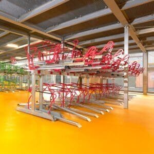 Etage fietsenrek met rode beugels in moderne fietsenstalling