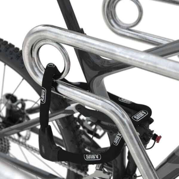 fietsenrek staal kopen Detail van een fiets die stevig is vastgemaakt met een slot aan het geïntegreerde slotoog van een verzinkt fietsenrek.