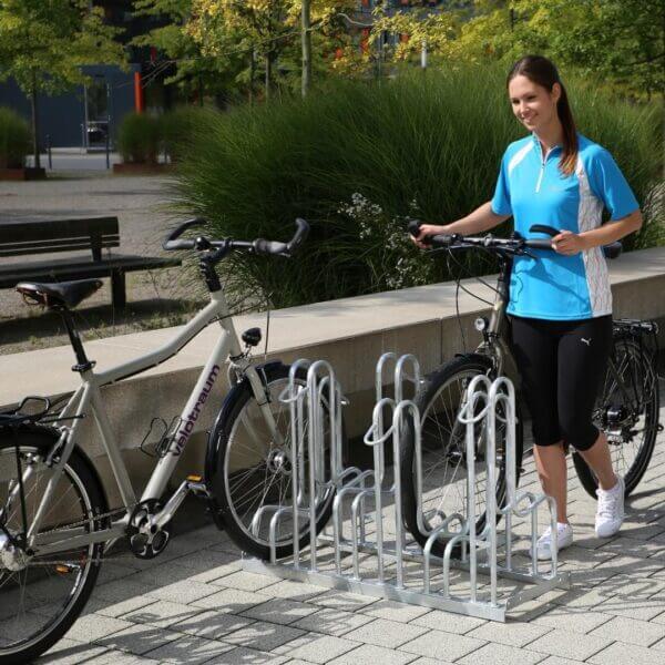 fietsenrek-schijfremmen-bestellen Vrouw plaatst fiets met schijfremmen in verzinkt fietsenrek met voorwielondersteuning