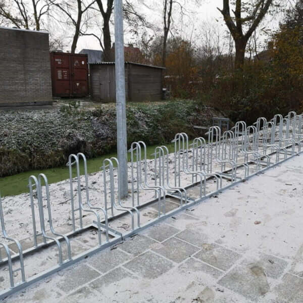 fietsenrek-online-aanschaffen Verzinkte fietsenrekken op stoeptegels bij een sloot, geschikt voor schijfremmen en met voorwielondersteuning