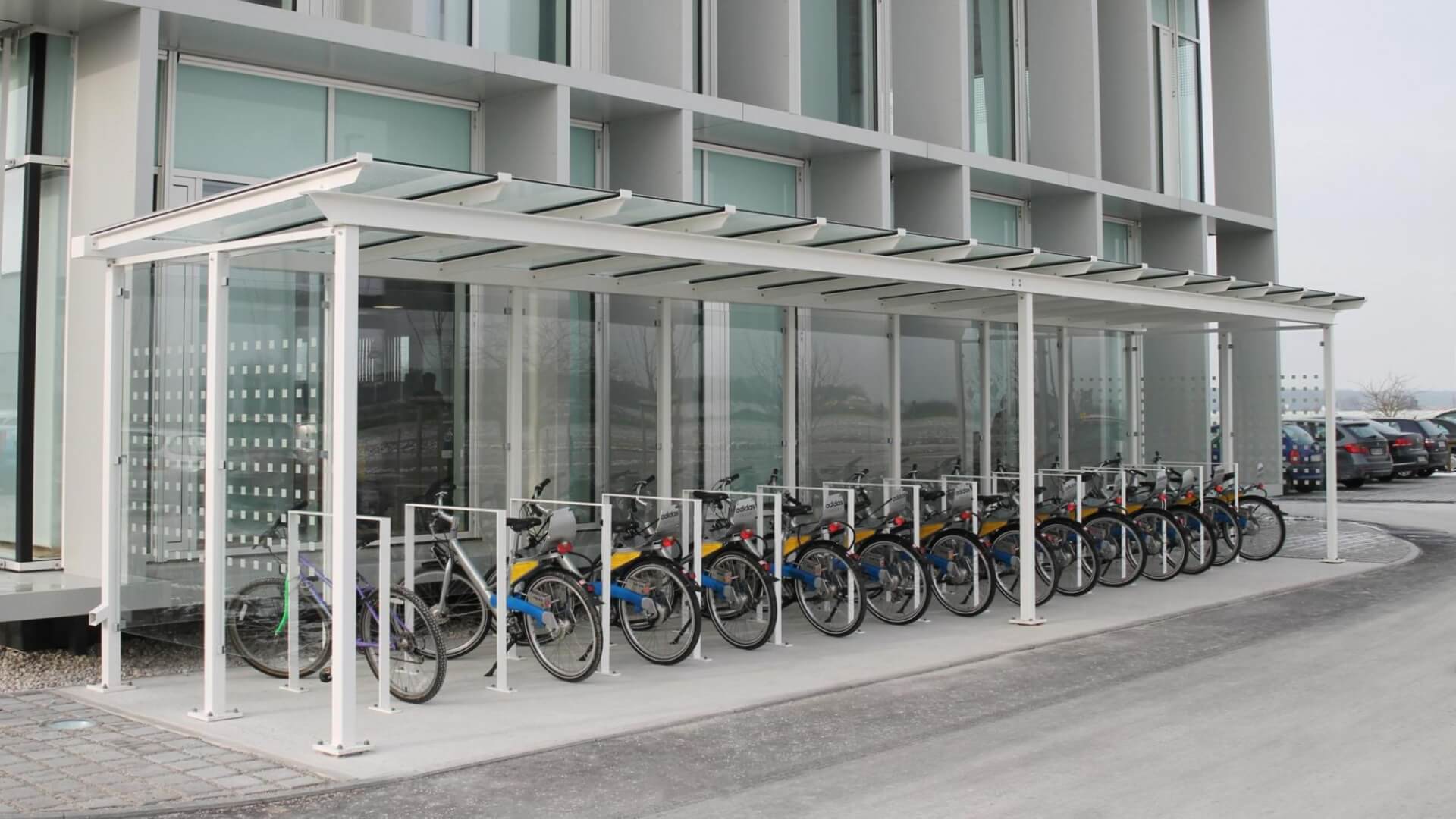 Fietsoverkapping van glas en staal met krijtkleur en fietsnietjes