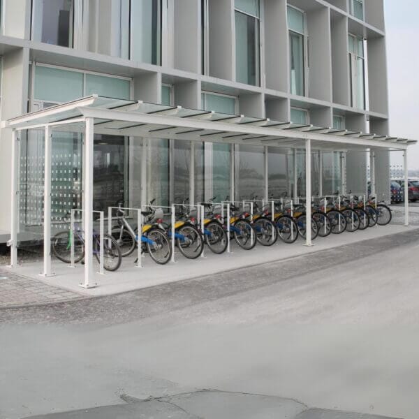 Fietsoverkapping bestellen voor bedrijven en instellingen Fietsenstalling met witte overkapping en fietsnietjes naast modern gebouw
