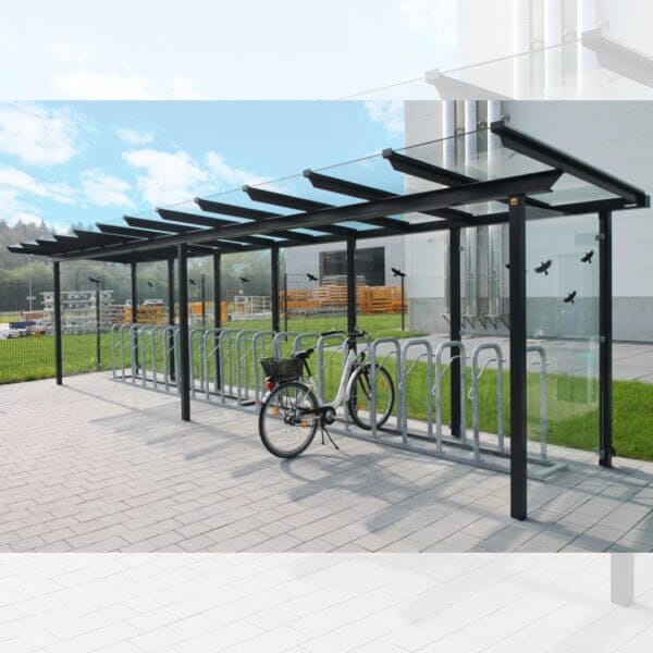 Moderne fietsoverkapping met glazen dak en zijwanden, inclusief geïntegreerde fietsnietjes.