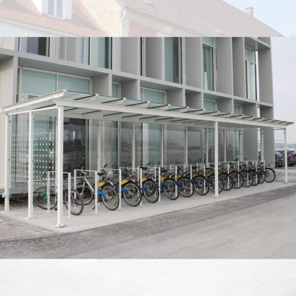 Fietsenberging aanschaffen Strakke fietsenberging met glazen dak en wanden, uitgerust met optionele fietsaanleunbeugels en zeefdrukpanelen, gemonteerd op een betonnen ondergrond.