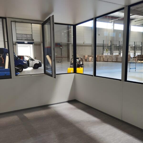 Kantoorunit 4x2m W Serie W12 Zonder Vloer Kopen Binnenkant van een kantoorunit met veel ramen, geplaatst in een bedrijfshal