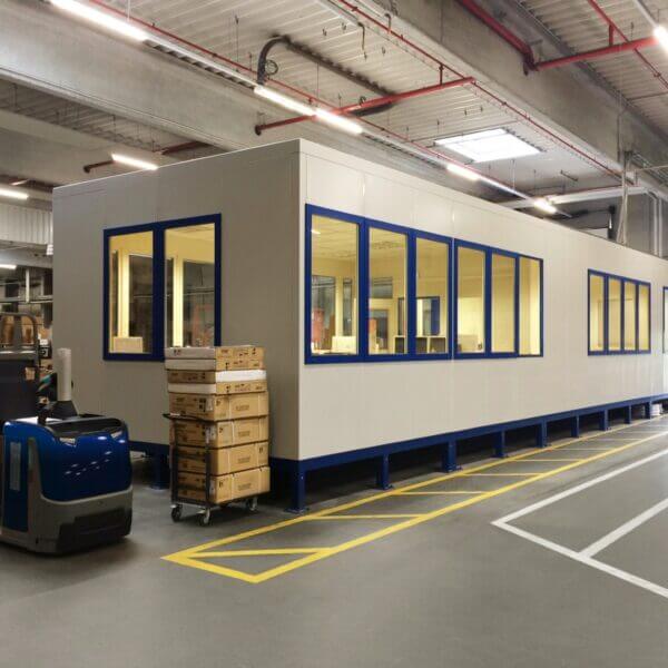 Kantoorunit voor hallen Grote kantoorunit met ramen, geschikt voor werkruimtes in fabrieksomgevingen.