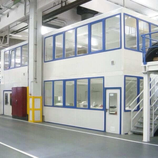 Kantoorunit op twee verdiepingen met trap Twee verdiepingen van een prefab kantoorunit met trap en ramen in een industriële omgeving.