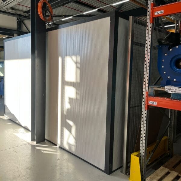 maatwerk-kantoorunit-aanschaffen Achterwand van een kantoorunit voor binnen in grijs en geplaatst in een magazijn.