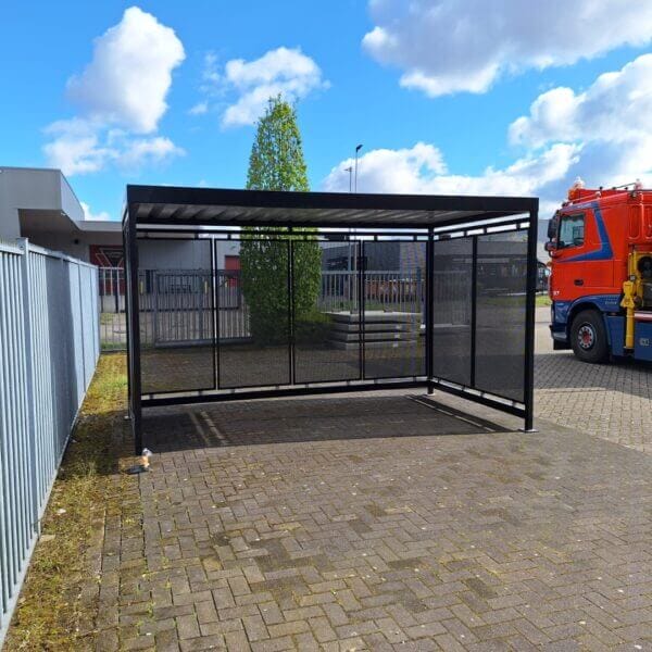 Rokersoverkapping van 4x2 meter direct online aanschaffen Rokersoverkapping en fietsoverkapping van 4x2 meter met zwarte stalen constructie en geperforeerde zij- en achterwanden op parkeerterrein.
