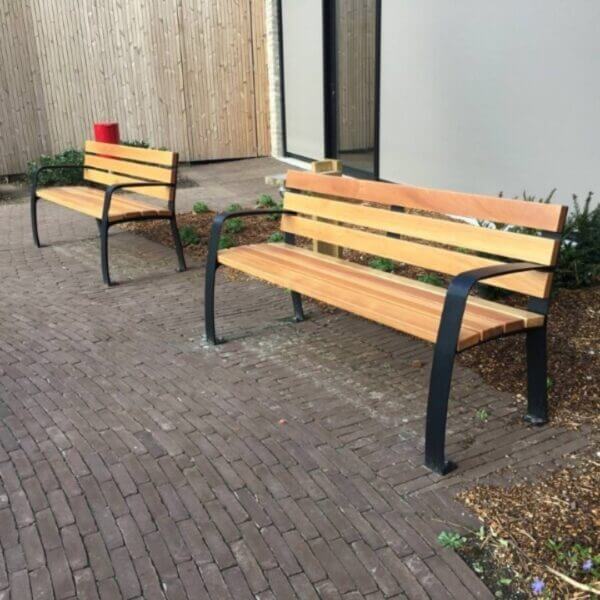 parkbank-senior-8 Twee seniorenbanken met houten latten en zwart stalen frame op klinkerbestrating.