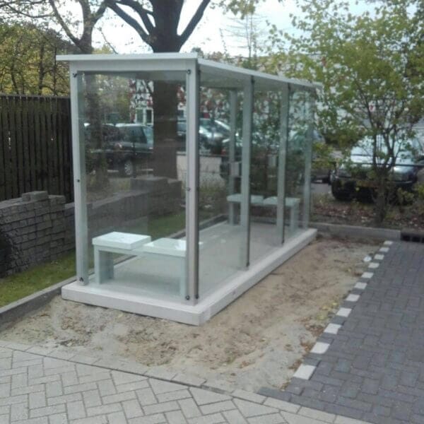 Rookabri Hunze 390x150 cm op betonplaat kopen Prefab rookabri Hunze van 390x150 cm met volledig glazen wanden, geïntegreerde zitbank en geleverd op een prefab betonplaat.