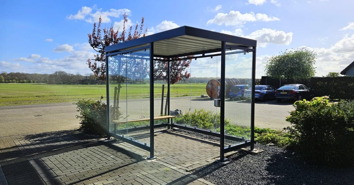 Rookruimte met glazen wanden, antraciet stalen frame, houten zitbankje en geïntegreerde RVS asbak