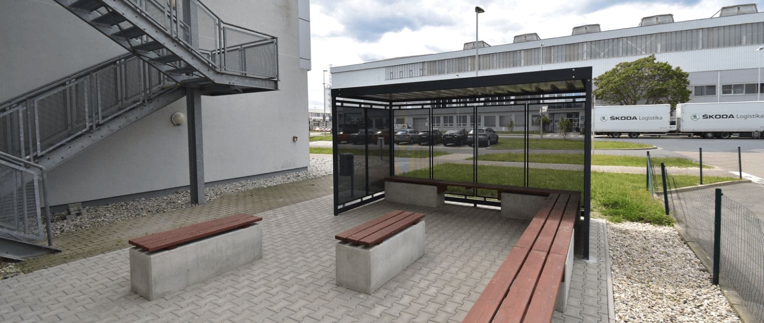 Overdekte rookruimte voor buitengebruik met stalen constructie, glaswanden en vaste banken.