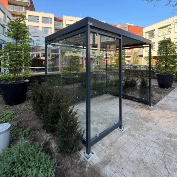 rookabri antraciet 3x2m staal glas kopen Rookoverkapping antraciet staal en glas geplaatst bij appartementencomplex