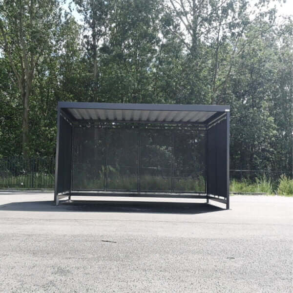 Rookoverkapping RAL 7016 met geperforeerd stalen wanden Vrijstaande rookoverkapping met geperforeerde stalen wanden in RAL 7016, verankerd op asfalt.